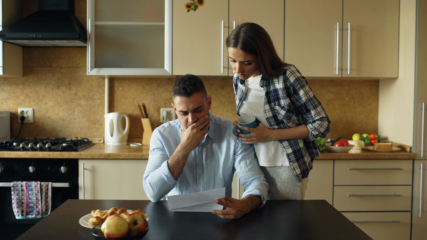 Casal preocupado lê contas na mesa da cozinha