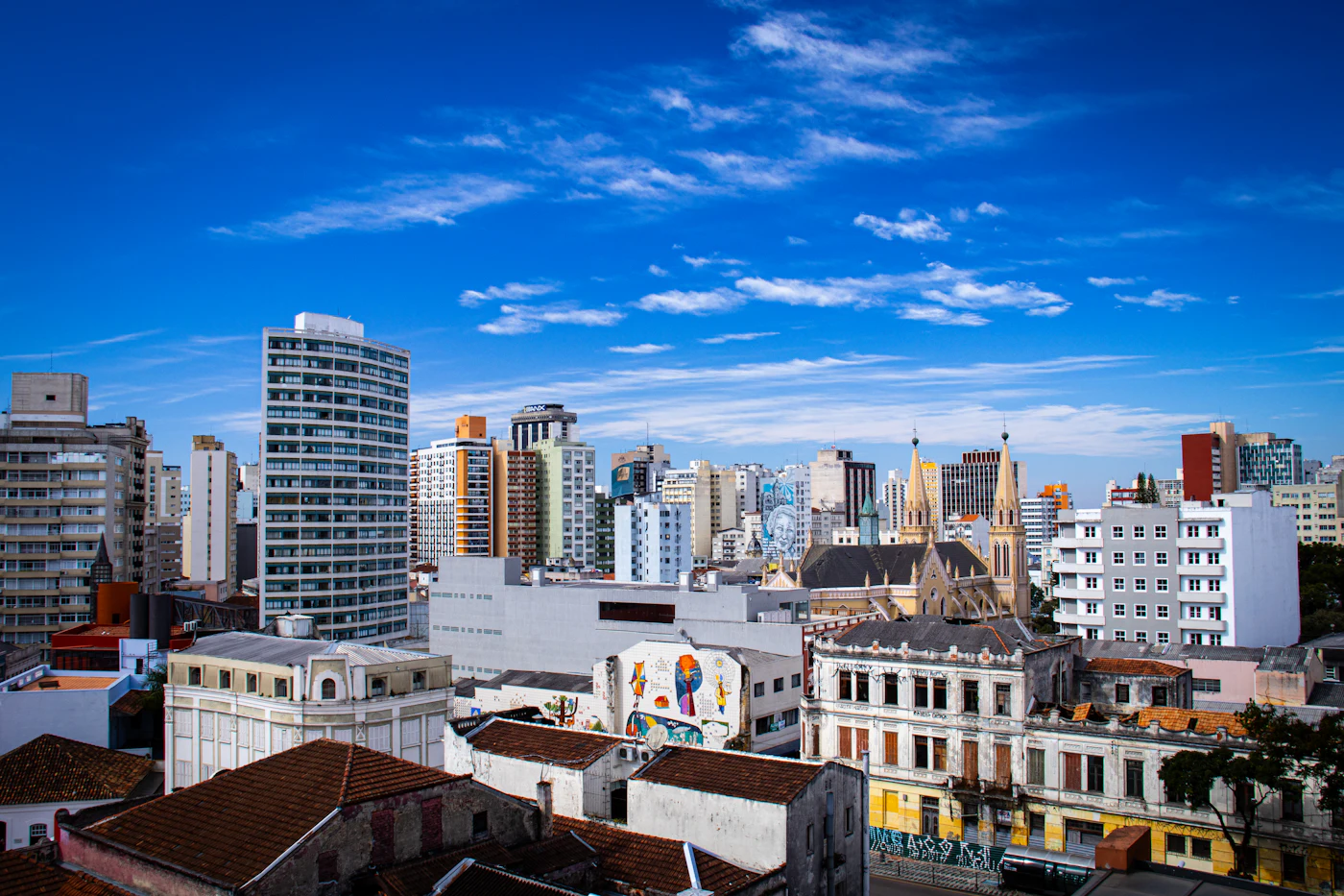 Vista de uma cidade com prédios altos e casas antigas sob o céu azul